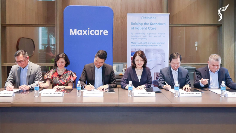 Executives from Shinagawa Diagnostic & Preventive Care and Maxicare sit together during a partnership event, with branding banners and nameplates displayed in front.