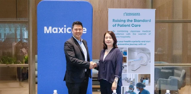 Shinagawa Diagnostic & Preventive Care representative and Maxicare executive shake hands in front of branded banners, symbolizing renewed partnership for advanced patient care.