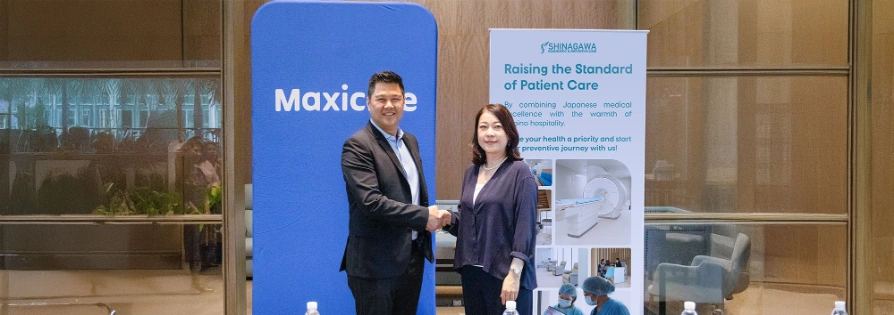 Shinagawa Diagnostic & Preventive Care representative and Maxicare executive shake hands in front of branded banners, symbolizing renewed partnership for advanced patient care.