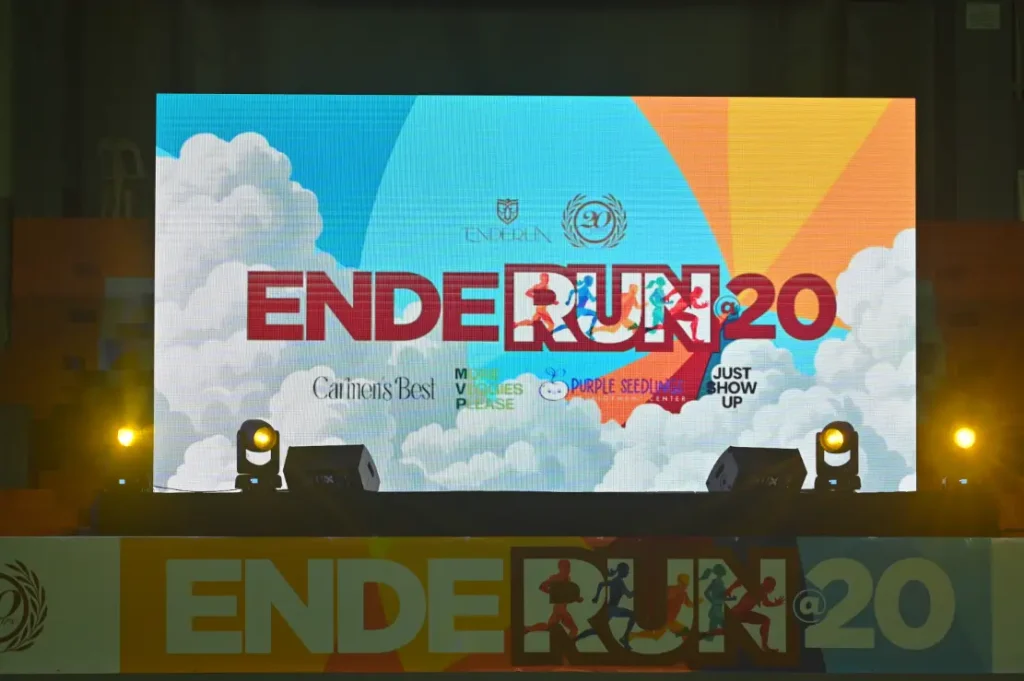 Colorful stage backdrop displaying the Enderun @20 EnderRun event logo with sponsor names and graphics, celebrating Enderun Colleges' 20th anniversary.