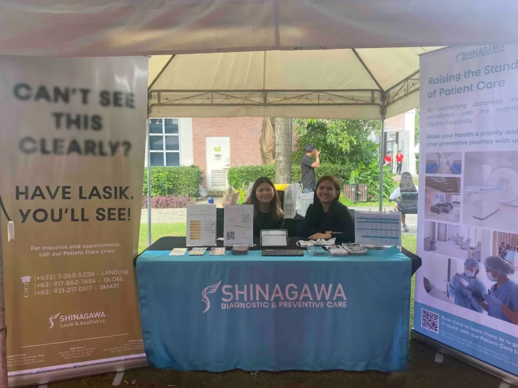 Shinagawa Diagnostic & Preventive Care team at an outdoor LASIK awareness booth with informational banners, brochures, and appointment sign-up table during a campus health event.
